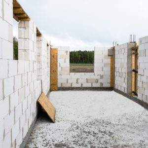 The walls of a house built of white brick with reinforced concrete pillars at the end of which there